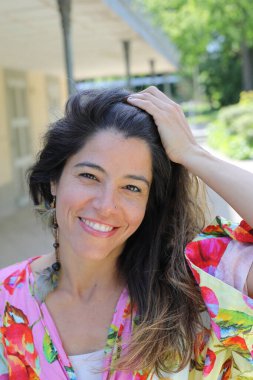 Mutlu genç kadın yaz elbisesi içinde poz veriyor.