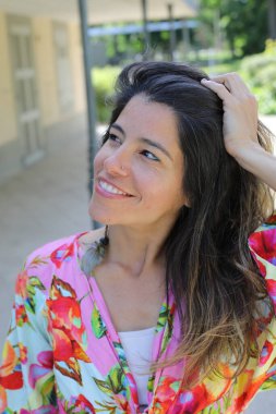 Mutlu genç kadın yaz elbisesi içinde poz veriyor.