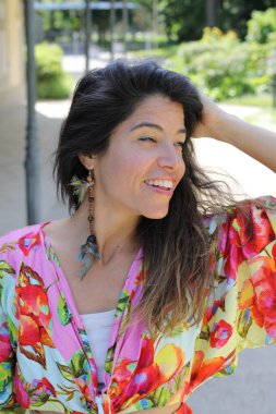 Mutlu genç kadın yaz elbisesi içinde poz veriyor.