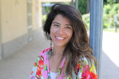 Mutlu genç kadın yaz elbisesi içinde poz veriyor.