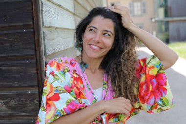 Mutlu genç kadın yaz elbisesi içinde poz veriyor.