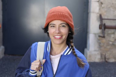 Sırt çantalı gülümseyen genç bir kadının portresi