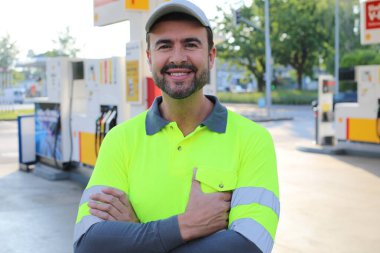 Mutlu gülüşü ve kendine güveni olan genç yakışıklı adam şehirde benzin istasyonunda duruyor.