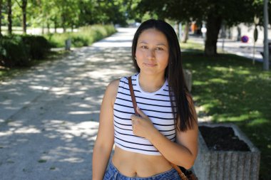 İspanyol kadın gülümsüyor ve parkta kameraya bakıyor.