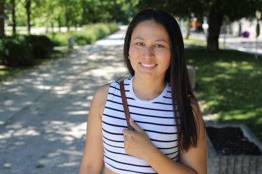 İspanyol kadın gülümsüyor ve parkta kameraya bakıyor.