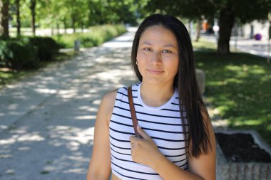 İspanyol kadın gülümsüyor ve parkta kameraya bakıyor.