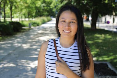 İspanyol kadın gülümsüyor ve parkta kameraya bakıyor.