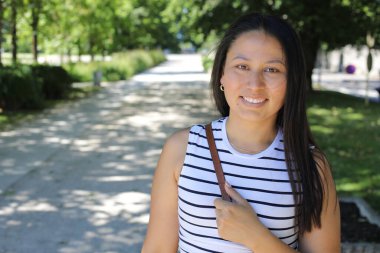 İspanyol kadın gülümsüyor ve parkta kameraya bakıyor.