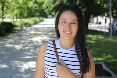 İspanyol kadın gülümsüyor ve parkta kameraya bakıyor.