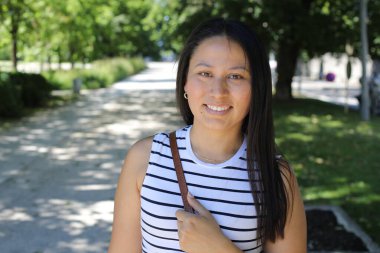 İspanyol kadın gülümsüyor ve parkta kameraya bakıyor.