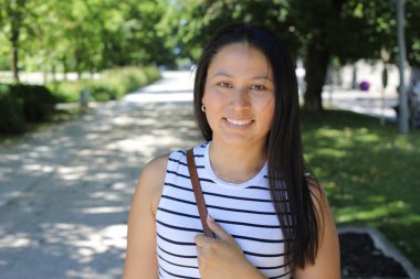 İspanyol kadın gülümsüyor ve parkta kameraya bakıyor.