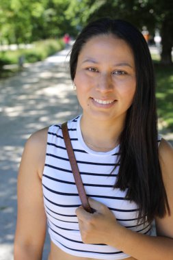 İspanyol kadın gülümsüyor ve parkta kameraya bakıyor.