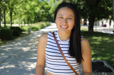 İspanyol kadın gülümsüyor ve parkta kameraya bakıyor.