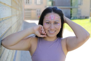 Yüzünde parlak taşlar olan eğlenceli bir kadın. 