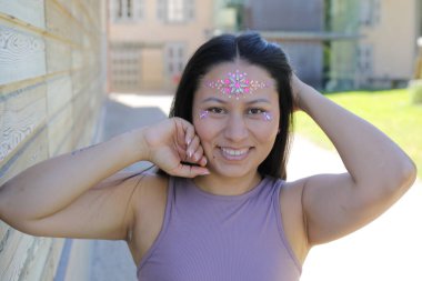 Yüzünde parlak taşlar olan eğlenceli bir kadın. 