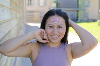 Yüzünde parlak taşlar olan eğlenceli bir kadın. 