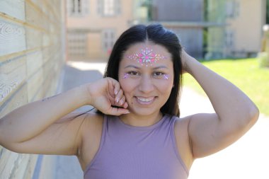 Yüzünde parlak taşlar olan eğlenceli bir kadın. 