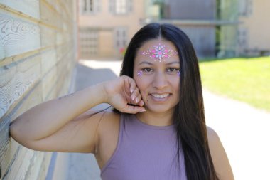 Yüzünde parlak taşlar olan eğlenceli bir kadın. 