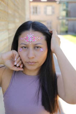 Yüzünde parlak taşlar olan eğlenceli bir kadın. 