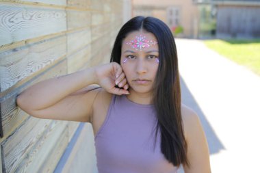 Yüzünde parlak taşlar olan eğlenceli bir kadın. 