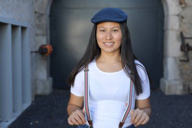 Pantolon askısı ve klasik şapka takan bir kadın. 