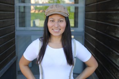 Pantolon askısı ve klasik şapka takan bir kadın. 