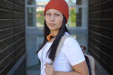 Yirmili yaşlarda çok güzel bir kız öğrenci sırt çantasıyla sokakta yürüyor.