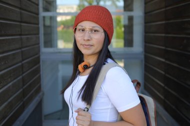 Yirmili yaşlarda çok güzel bir kız öğrenci sırt çantasıyla sokakta yürüyor.