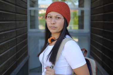 Yirmili yaşlarda çok güzel bir kız öğrenci sırt çantasıyla sokakta yürüyor.