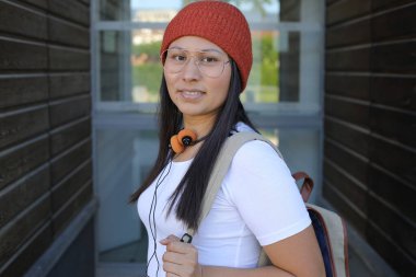 Yirmili yaşlarda çok güzel bir kız öğrenci sırt çantasıyla sokakta yürüyor.