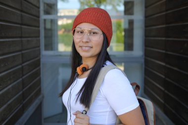 Yirmili yaşlarda çok güzel bir kız öğrenci sırt çantasıyla sokakta yürüyor.