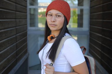 Yirmili yaşlarda çok güzel bir kız öğrenci sırt çantasıyla sokakta yürüyor.