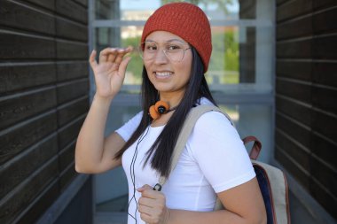 Yirmili yaşlarda çok güzel bir kız öğrenci sırt çantasıyla sokakta yürüyor.