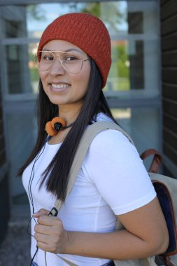 Yirmili yaşlarda çok güzel bir kız öğrenci sırt çantasıyla sokakta yürüyor.