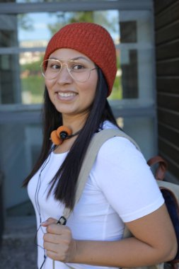 Yirmili yaşlarda çok güzel bir kız öğrenci sırt çantasıyla sokakta yürüyor.