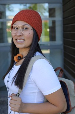 Yirmili yaşlarda çok güzel bir kız öğrenci sırt çantasıyla sokakta yürüyor.