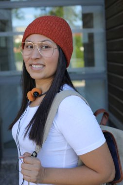 Yirmili yaşlarda çok güzel bir kız öğrenci sırt çantasıyla sokakta yürüyor.