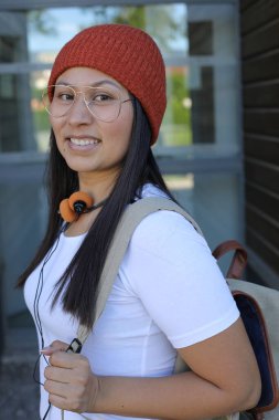 Yirmili yaşlarda çok güzel bir kız öğrenci sırt çantasıyla sokakta yürüyor.