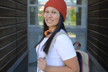 Yirmili yaşlarda çok güzel bir kız öğrenci sırt çantasıyla sokakta yürüyor.