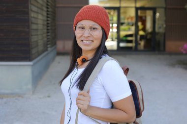 Yirmili yaşlarda çok güzel bir kız öğrenci sırt çantasıyla sokakta yürüyor.