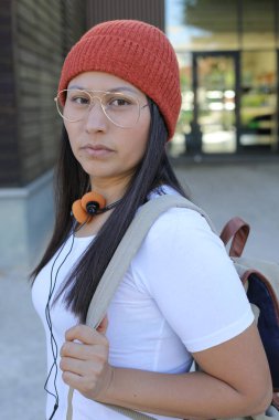 Yirmili yaşlarda çok güzel bir kız öğrenci sırt çantasıyla sokakta yürüyor.