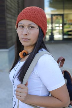 Yirmili yaşlarda çok güzel bir kız öğrenci sırt çantasıyla sokakta yürüyor.