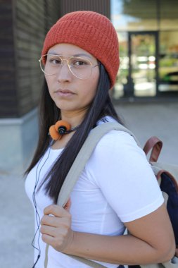 Yirmili yaşlarda çok güzel bir kız öğrenci sırt çantasıyla sokakta yürüyor.