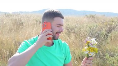 Akıllı telefonlu buğday tarlasında yakışıklı bir adam.