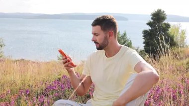 Yakışıklı bir adam telefonuna mesaj yazıyor doğal ortamında. 