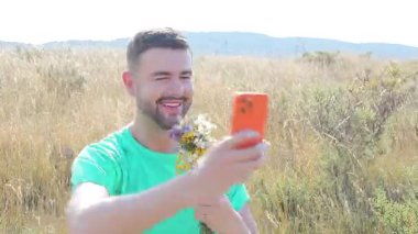 Akıllı telefonlu buğday tarlasında yakışıklı bir adam.