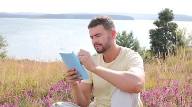 Göl kenarındaki defterde yazan yakışıklı adam.