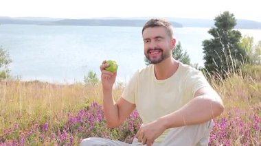  Genç adam doğada elma yiyor.
