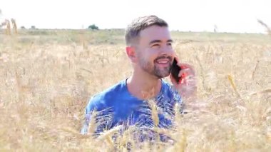 Akıllı telefonlu buğday tarlasında yakışıklı bir adam.