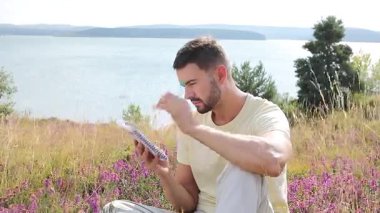 Mutlu adam göl kenarında deftere yazıyor.